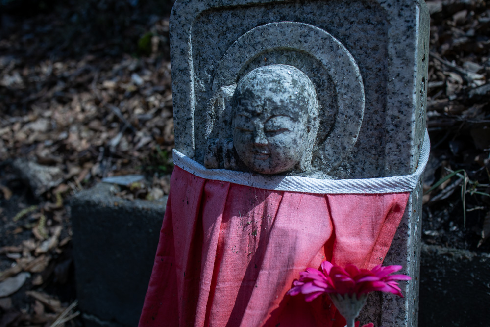 A small Buddha statue wearing a red apron. 
