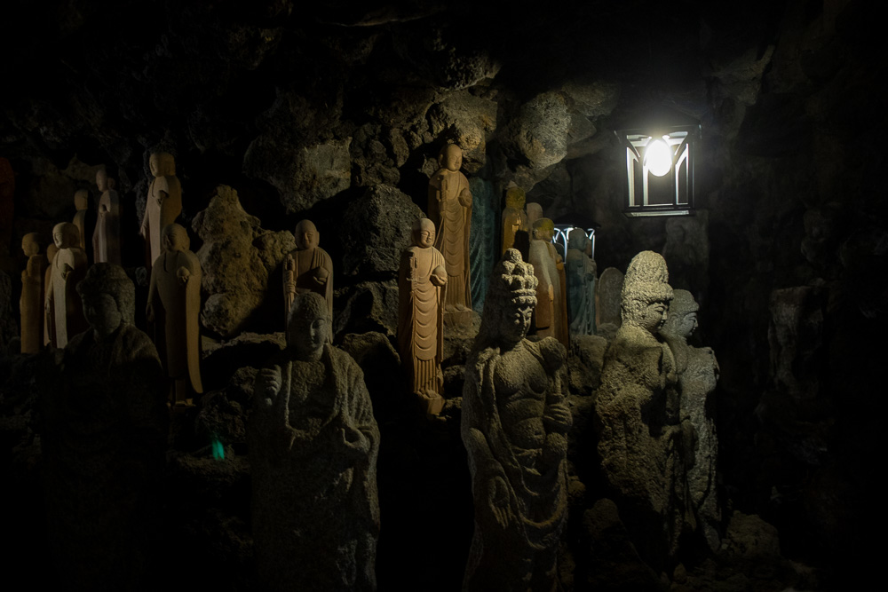 Dozens of Buddha statues in an underground cave.